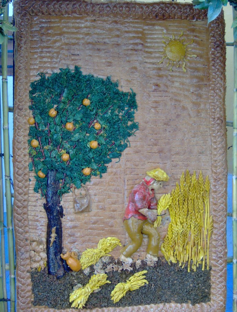 Archi di Pane bread artwork depicting farmer harvesting grain under the hot Sicilian sun. Beside them is a fruit tree complete with a bag (no doubt containing their lunch) and a lizard climbing the trunk.